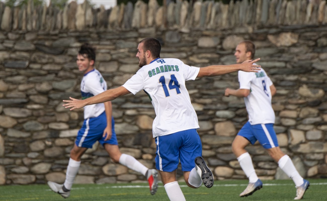 soccer playing running with both arms out stretched near two other players