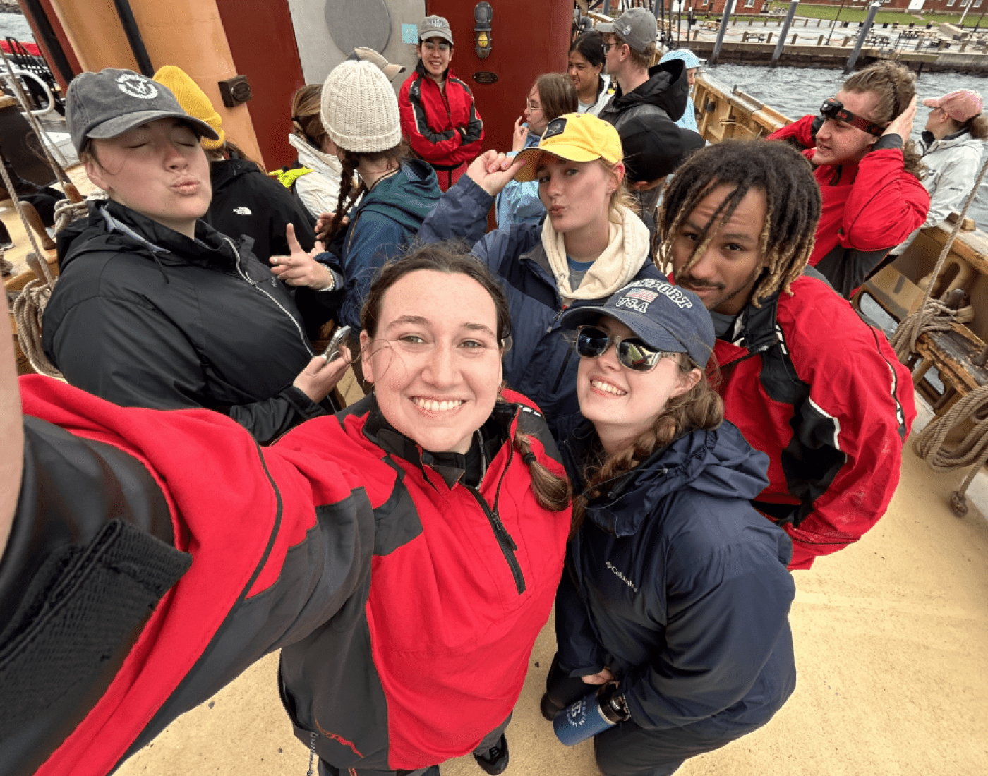 Smiling students take a group selfie aboard a ship