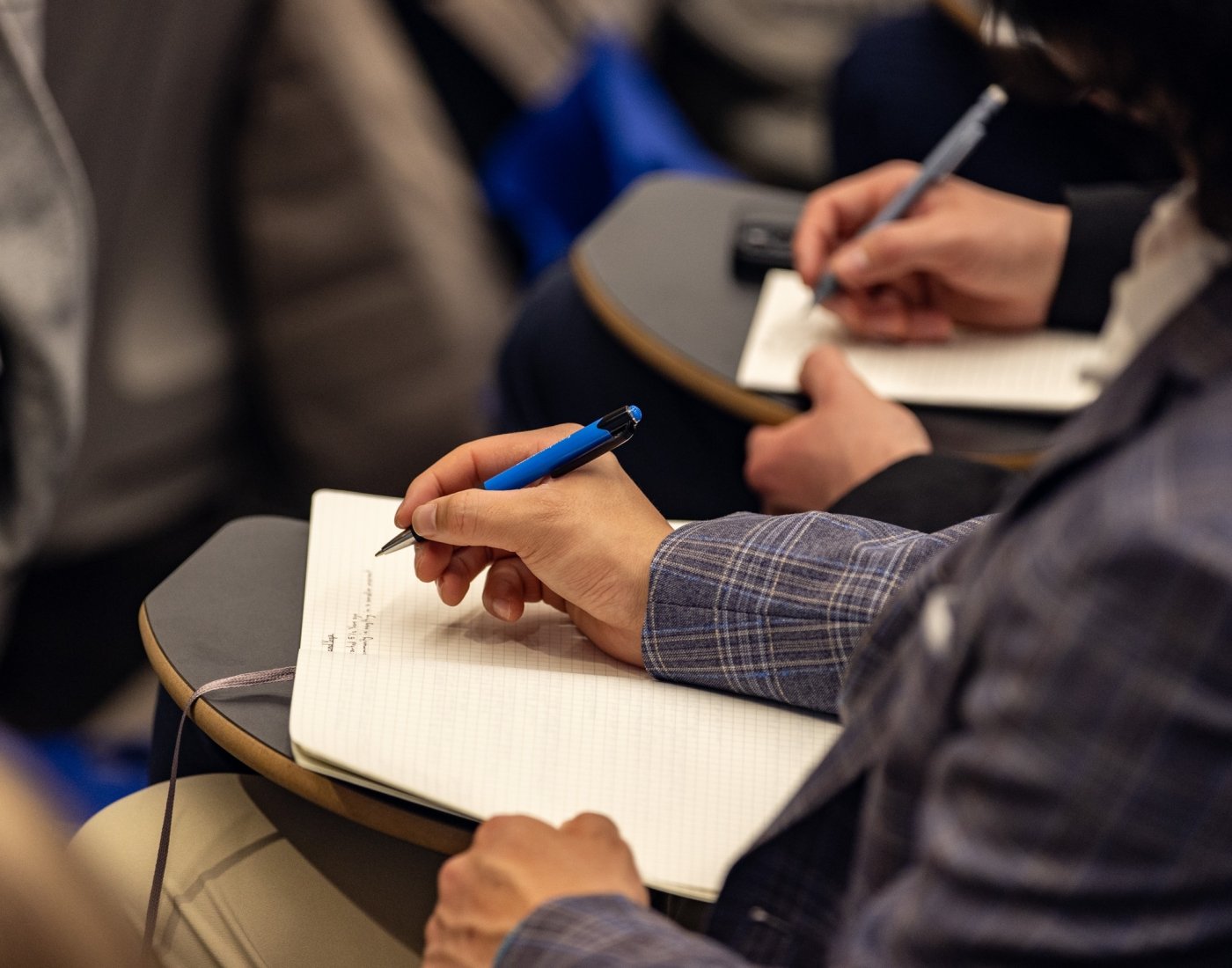 looking down at person sitting in desk writing notes in notebook
