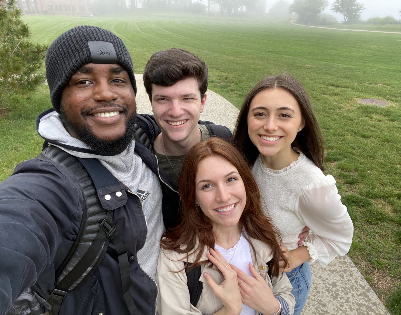 Group of 4 students taking a selfie on the lawn with fog in background
