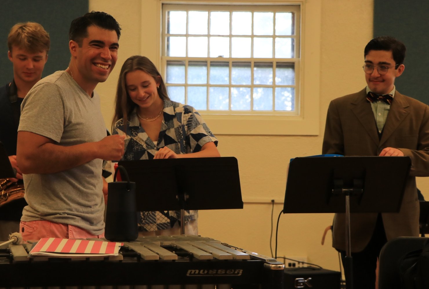Students smiling in a music room behind their music stands.