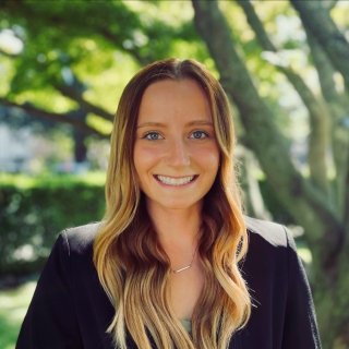 Professional headshot of Morgan Shuey smiling under the shade of a tree