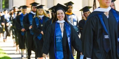 graduates processing as part of commencement with focus on female student smiling in line