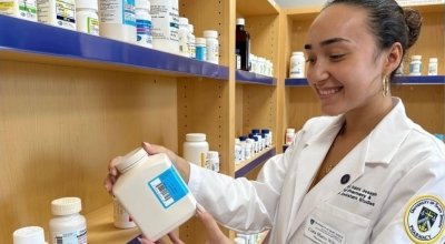 Marro-Wilson in white lab coat looking at a pill bottle.
