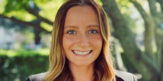 Professional headshot of Morgan Shuey smiling under the shade of a tree