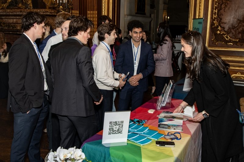 Male business students dressed professionally talking with businesswoman at a table for the Career and Internship Expo