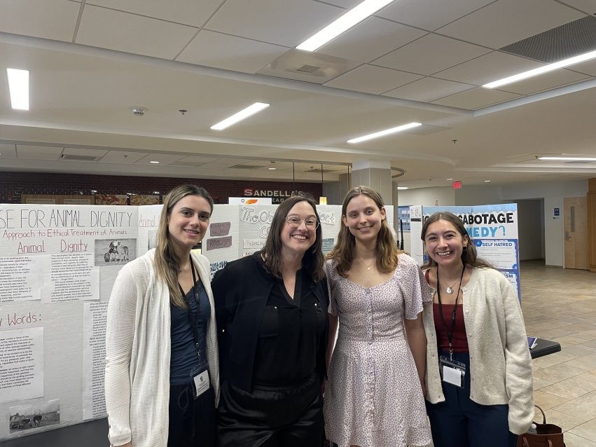 Brennan and students in front of posterboard.